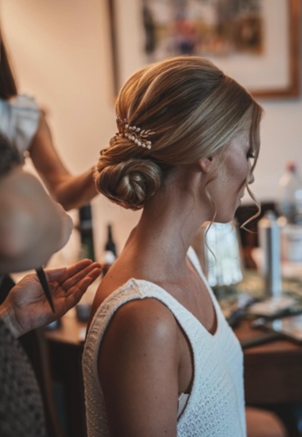 Haarschmuck wird in einen tief sitzenden Chignon gesteckt, Blick über die Schulter vor dem Spiegel
